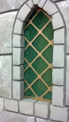 a close up of a window in a brick wall with green and white tiles on it