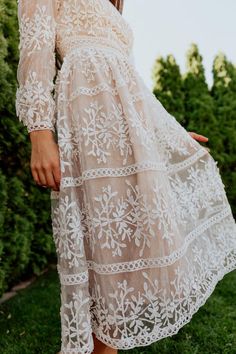 a woman in a white dress is standing outside