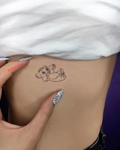 a woman's stomach with a small tattoo on the side of her belly, which has a teddy bear drawn on it