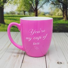 a pink coffee mug with the words hello gorgeous on it sitting on a wooden table