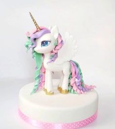 a white cake topped with a pink and green pony