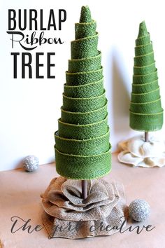 the burlap ribbon tree is sitting on top of a table next to two small trees