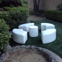 four white chairs sitting on top of a lush green field