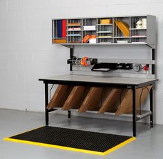 a metal workbench with several files and tools on it in front of a white wall