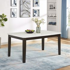 a table with two bowls of fruit on it in front of a blue area rug