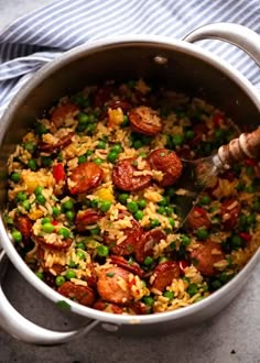 a pot filled with rice, peas and sausage