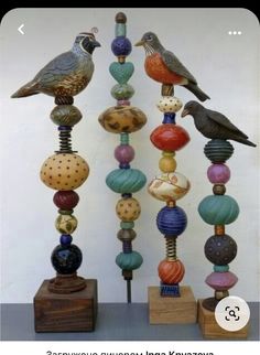 two birds sitting on top of different colored beads and wooden blocks in front of a white wall