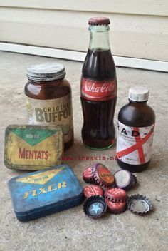 some old soda bottles and tins sitting on the ground next to each other in front of a door