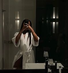 a woman taking a selfie in front of a bathroom mirror with her cell phone