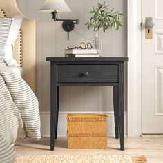 a nightstand with a plant on top of it next to a bed in a bedroom