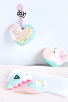 two stuffed animals hanging from hooks on a white wall next to a pink and blue heart