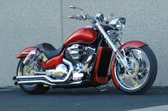 a red motorcycle parked next to a wall