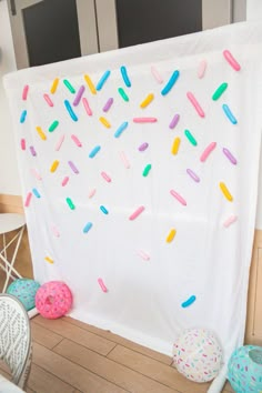 a white backdrop with sprinkles and donuts hanging on it's side