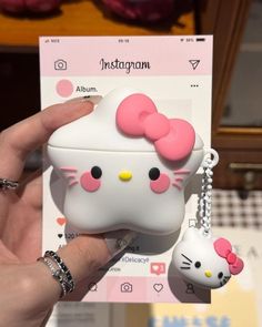 a person holding up a hello kitty airpods case with a keychain attached to it