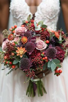 a bridal holding a bouquet of flowers and berries