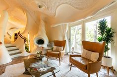 a living room filled with furniture and lots of windows next to a spiral stair case