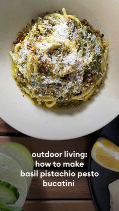 a white bowl filled with pasta on top of a wooden table next to sliced lemons