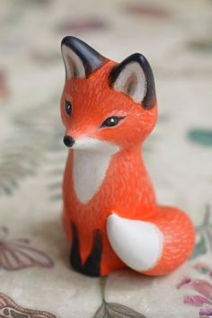 a small figurine of a fox sitting on top of a floral table cloth