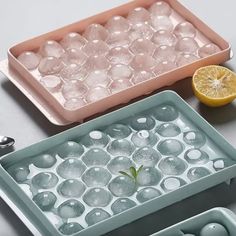 three trays with lemon slices and ice cubes in them on a gray surface