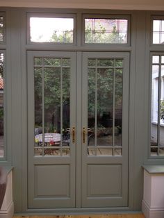 the front door to a house with double glass doors and windows on both sides,