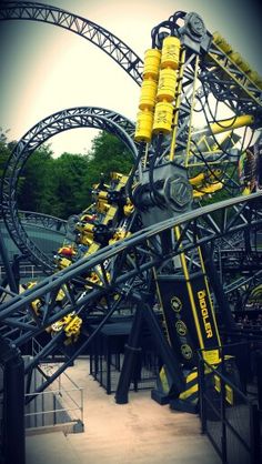 the roller coaster at an amusement park is yellow and gray with black details on it