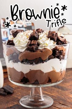 a brownie trifle in a glass dish on a wooden table with the title above it