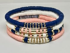 Set of 4 Navy, Light Coral, and White, hand beaded, stretch bracelets. Bracelets are made with 6mm Heishi beads with gold accents. Can customize with wording of your choice using white beads with gold letters. Cute Heishi Bracelets Ideas, Heshi Bead Ideas, Bracelets Stacking, Bracelet Heishi, Heishi Jewelry, Navy Bracelet, Womens Gifts, Stacked Bracelets, Bracelets Boho