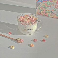 a cup filled with cereal sitting on top of a table next to a box of cereal