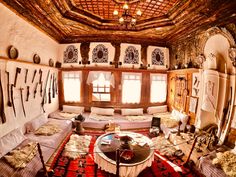 a living room filled with lots of furniture and decor on top of a red rug