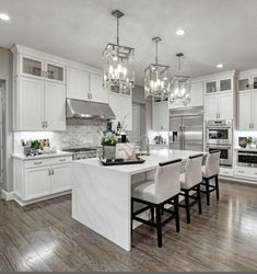 a large kitchen with white cabinets and marble counter tops, an island in the middle