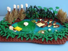 a lego model of a pond with plants and animals