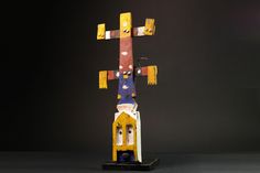 a colorful wooden cross on top of a black surface