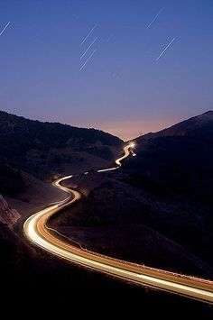 an aerial view of a winding road at night with stars in the sky above it