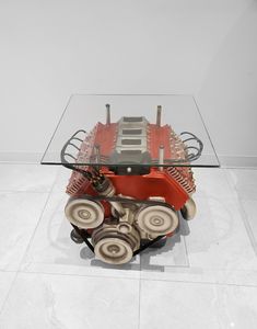 a glass table with wheels on it in the shape of a car engine and gears