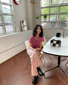 a woman sitting on a chair in front of a table with a handbag on it