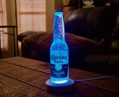 an illuminated beer bottle sitting on top of a wooden table