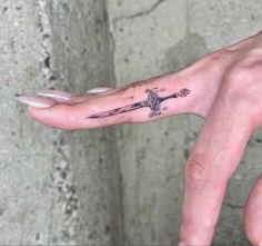 a person's hand with a cross tattoo on it and a knife in the middle