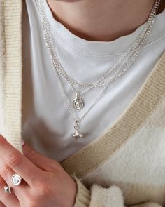 a woman is holding two necklaces on her hand