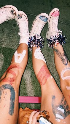 two people with their legs covered in paint and holding a cell phone on the ground