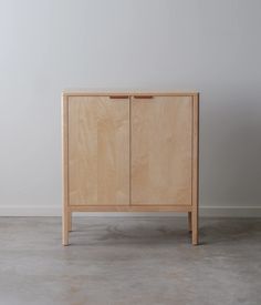 a wooden cabinet sitting on top of a cement floor next to a white wall in an empty room