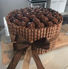 a cake with chocolates in it on top of a glass plate and brown ribbon