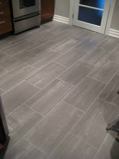 a kitchen with gray tile flooring and stainless steel appliances