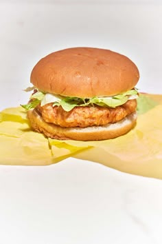 a chicken sandwich with lettuce and mayonnaise on a piece of wax paper