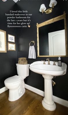 a white toilet sitting under a bathroom mirror next to a sink in a room with black walls