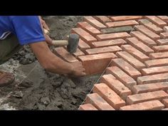 a man is laying bricks on the ground