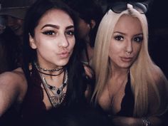 two beautiful young women sitting next to each other in front of a crowd at a party