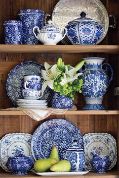 blue and white china on shelves with flowers in vases, pears and apples