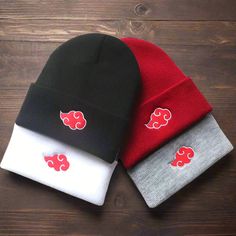 three beanies with red, white and black designs on them sitting on a wooden surface