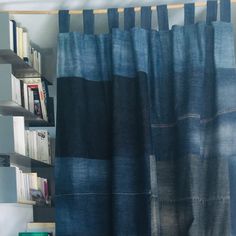 there is a book shelf with several books on it next to a curtain in the room