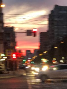 cars are driving down the street at dusk in an urban area with high rise buildings and traffic lights